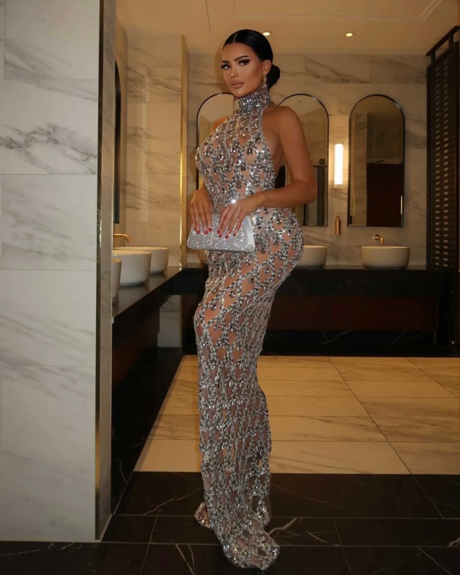 a woman in a silver dress standing in a bathroom